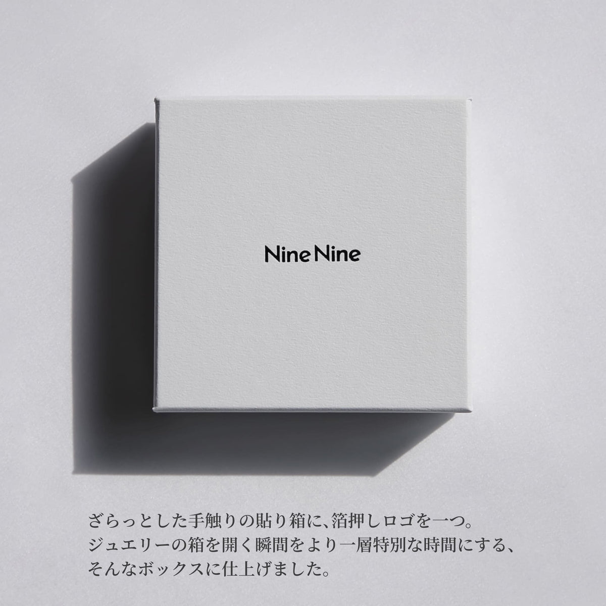 Nine Nineのロゴが中央に箔押しされた、さらりとした質感のホワイトボックス。やわらかな光と影が落ちるミニマルなパッケージイメージ。