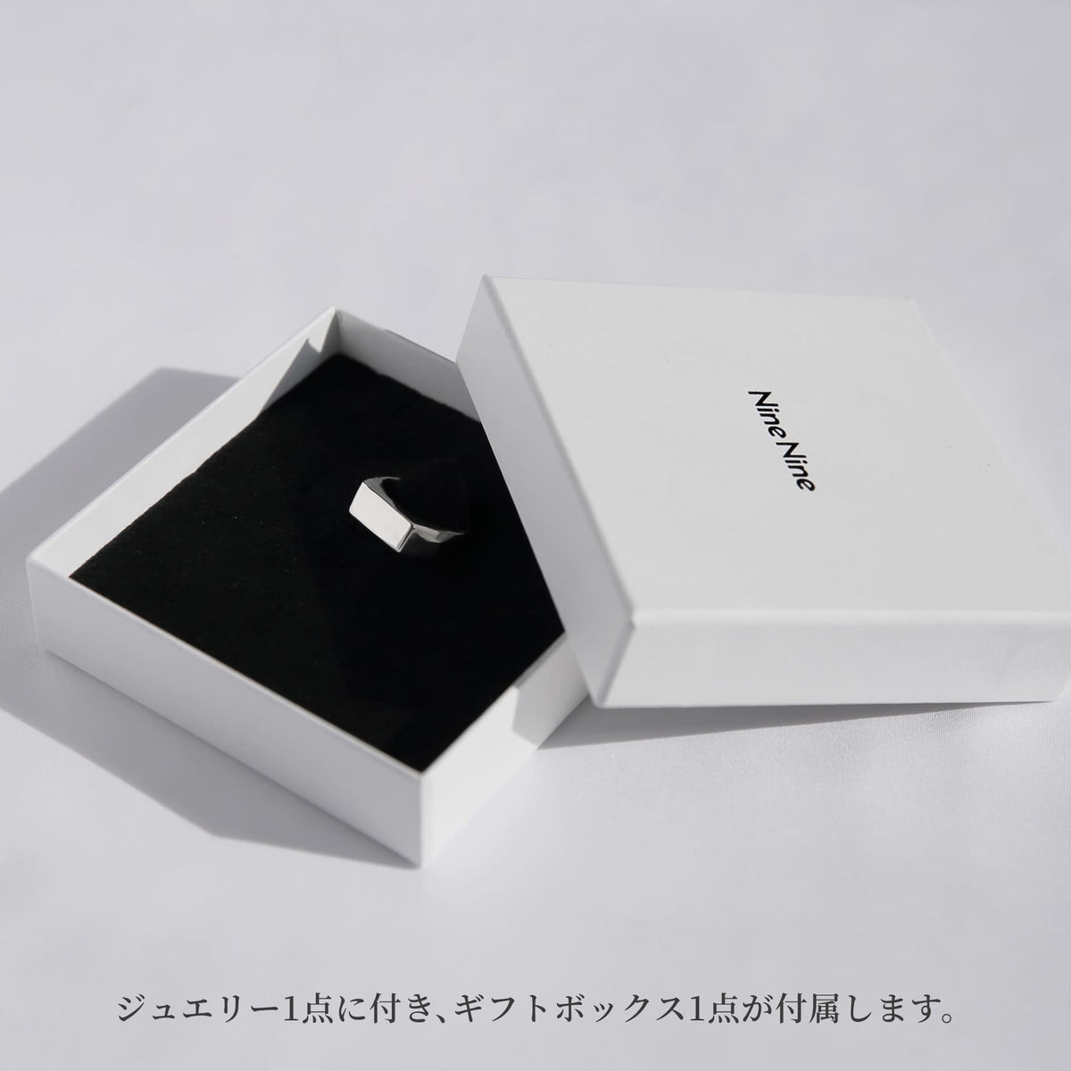 Nine Nineのロゴ入りホワイトギフトボックスを開けた状態のイメージ。黒いクッションにシルバーリングをセットしたパッケージ写真。ジュエリー1点につきギフトボックス1点が付属することを示すビジュアル。
